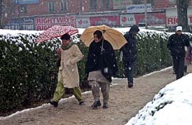 Women walk near the snow as it falls in Srinagar