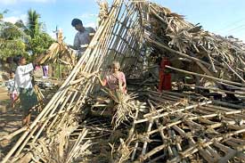 A family tries to rebuild its bamboo hut that was damaged by a cyclone in Machilipatnam, Andhra Pradesh