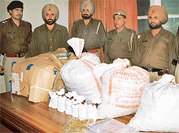 Patiala police personnel show bags and a cardboard box containing 96 kg of charas worth Rs 50 crore found from near a sick unit in Sarseeni village near Lalru on Thursday.