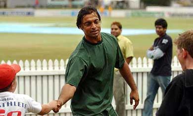 Pakistan's Shoaib Akhtar thanks children for an impromptu game of cricket on the grass embankment between two rubbish bins 