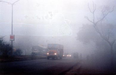The mantle of thick fog forces vehicle drivers on a highway to switch on lights in Ludhiana