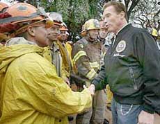 California Governor Arnold Schwarzenegger shakes hands with firefighters while surveying the destruction in Paso Robles