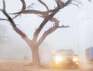A car with headlights on finds its way through the thick fog that enveloped Chandigarh