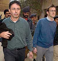 French journalists, Marc Epstein (left) and Jean-Paul Guilloteau, are cuffed to each other as they arrive at the district court in Karachi