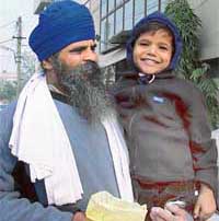Five-year-old Shivam in the arms of priest Sapinder Singh. 