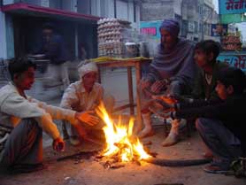 Workers sit near a bonfire during the day to keep the cold away in Ludhiana on Saturday