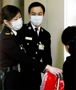 Customs officers wear protective masks as they check the baggage of a traveller upon her arrival from Guangzhou at Hong Kong's train terminal