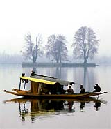 Kashmiris paddle their boat in the Dal Lake on a cold evening in Srinagar on Monday
