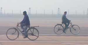 Only cyclists made headway on a day most flights were grounded. The Palam airport can be seen enveloped in the fog in the background.