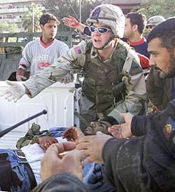 A US Army soldier treats a wounded Iraqi man after a roadside blast in a shopping area of Baghdad