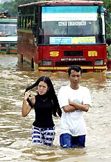 A couple wades through a flooded street following heavy overnight rains in Jakarta