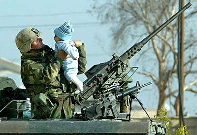 A US army soldier holds up a baby on top of his Humvee vehicle during a New Year's Eve party for orphans and poor children in a suburb of Baghdad