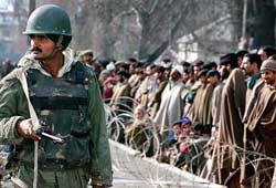A policeman stands guard as Kashmiris listen to speakers during a peace rally in Srinagar on Thursday.