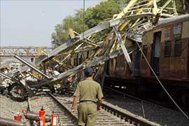 A policeman walks past a partly-constructed bridge which collapsed over a passing passenger train in a north-eastern suburb of Mumbai