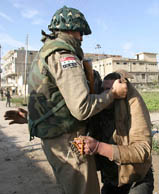 An Iraqi Civil Defence Corps (ICDC) soldier checks an Iraqi man during a joint patrol with the US soldiers in Tikrit