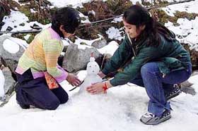 Children make a snowman at Lakkar Mandi tourist destination of Dalhousie during the first snowfall of this season on Friday.
