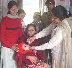 An employee of the Department of Health administers polio drops to a child in Hamirpur