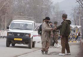 A BSF soldier checks a Kashmiri youth during a search operation in Srinagar on Sunday.