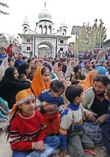 Sikh women and children listen to prayers at a Gurdwara on the eve of the 338th birth anniversary of Guru Gobind Singh, in Srinagar on Monday
