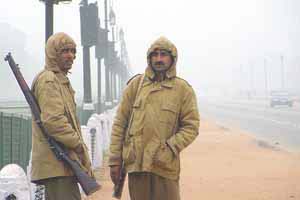 Security guards keeping a watchful eye on the India Gate covered by a thick layer of fog