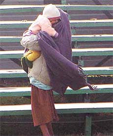 A woman trying to provide warmth to her child on a chilly afternoon in the Capital