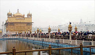 Devotees stand in queue to pay homage on the occasion of the 338th birth anniversary of Guru Gobind Singh at the Golden temple in Amritsar 