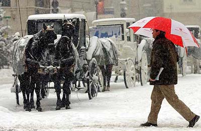 A man walks past horse-drawn carriages in central Vienna, Austria, 