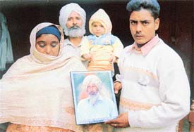 Ajit Singh�s widow carrying his picture with her son and brother-in-law in Siahar