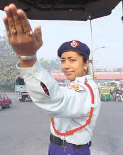 A woman police constable regulates traffic at the busy Tilak Marg crossing