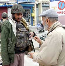 A soldier checks the identity card of a man during a raid on the main market in Central Srinagar on Wednesday. 