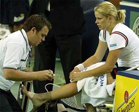 Kim Clijsters has her foot examined by physiotherapist Anthony McEvoy after she injured her achilles tendon during her match against Alicia Molik of Australia 