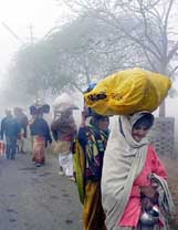 Villagers carry their belongings in an attempt to escape the ongoing cold spell in Allahabad