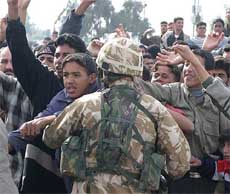 Demonstrators shout near a British soldier guarding the administration headquarters in the south-eastern city of Amarah 