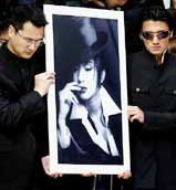 Hong Kong singer-actor Nicholas Tse (right) and a cousin of the late canto-pop diva Anita Mui carry a portrait of Mui during her funeral