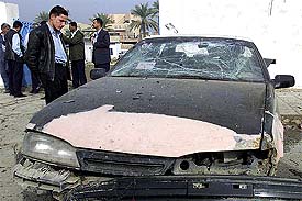 A man looks over the damage done to a vehicle after a suicide bomber blew up a car outside a police station in the Iraqi town of Baquba