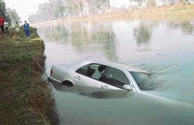 A Mercedes car lies partially submerged in the Sidhwan canal after it was hit by a tempo near South City