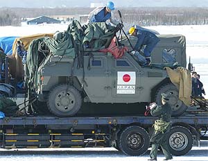 Workers remove the cover from a Japanese light armoured vehicle bound for Iraq