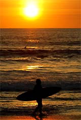 A surfer leaves the water at sunset near Kuta beach in Bali 