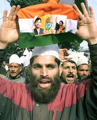A Kashmiri supporter of the Congress holds a party flag with photographs of its leaders during a rally in Jammu 