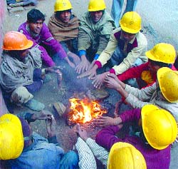 Metro workers huddle around a fire as strong winds lashed the Capital