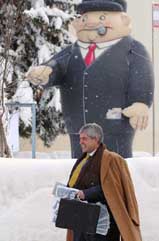 An anti-globalisation activist, acting as a corporate leader with a briefcase full of fake money, walks by an oversized doll representing another corporate leader advertising the conference, The public eye on Davos, in Davos, Switzerland 