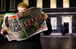 A journalist reads a tabloid that claims to have details from the leaked Hutton report