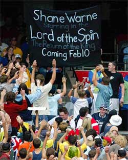 Crowd cheer towards a sign heralding the return of Australian spin-bowler Shane Warne 