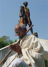 A man dressed as Mahatma Gandhi prays on his 56th death anniversary