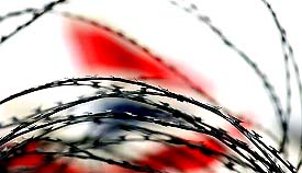 The tail-fin of a British Airways plane is seen behind barbed wire at London's Heathrow airport