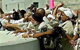 Pilgrims are held back by Saudi Arabian security officials at the beginning of the second day of throwing stones at pillars symbolising the Devil at Mena