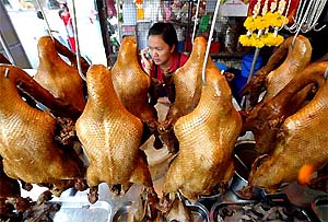 A Thai vendor selling roasted ducks awaits customers at a market in Bangkok on Monday