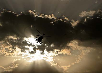 The early morning sun silhouettes an US OH-58 Kiowa surveillance army helicopter as it flies over Baghdad