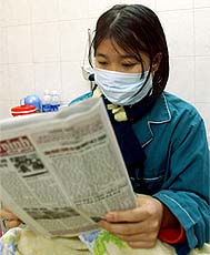 Vietnamese patient Le Thi Huong, 20, who has been confirmed as infected by bird flu, reads a newspaper on her bed at a hospital in Hanoi