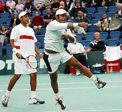 Leander Paes hits a return as his partner Mahesh Bhupathi looks on